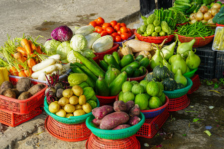 A diverse array of freshly harvested vegetables in colorful baskets displayed at a lively street market in Vietnamの写真素材