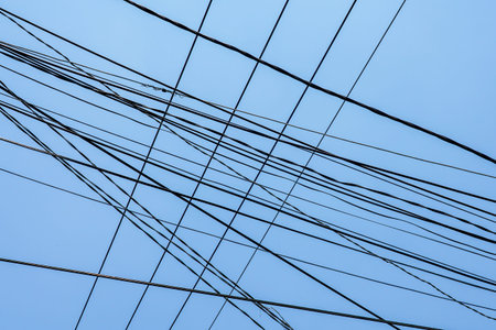 A chaotic web of power lines stretches across the sky, illustrating urban infrastructure in Vietnam...