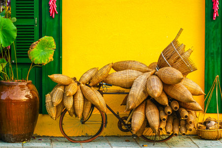 A bicycle stacked with handmade bamboo fish traps rests by a vibrant yellow wall, showcasing Vietnam rural charmの写真素材