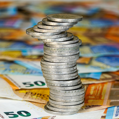 This photo shows a leaning tower of silver euro coins placed atop euro notes, highlighting finance,...