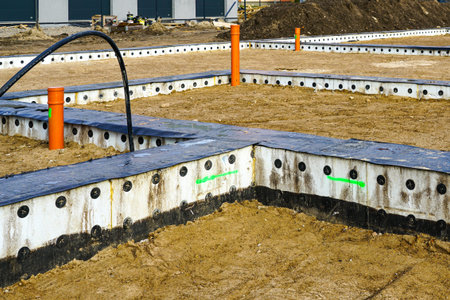 Insulated concrete strip foundation and utility pipes installed in the ground, marking the start of a new residential building projectの写真素材