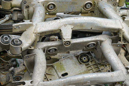 Close-up of used aluminum automotive suspension parts and frames with dirt and wear, stacked for recycling, scrap, or auto industry reuseの写真素材