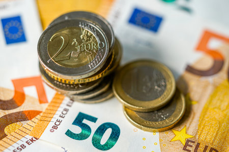 Close-up of euro coins stacked on 50 euro banknotes, representing European money, finance, savings, banking, and the eurozone economyの写真素材