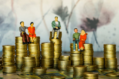 Miniature figurines sit on stacks of euro coins, symbolizing wealth, savings, investments, financial planning, prosperity, and secure economic growthの写真素材