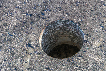 A close-up view of a core-drilled hole in asphalt pavement used for testing thickness, density, and quality of road construction materialの写真素材