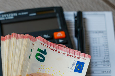 Ten euro banknotes with a calculator, pen, and documents on a table, representing finance, budgeting, accounting, and economic planning conceptsの写真素材