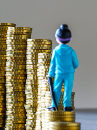 A miniature figure atop stacked gold coins, representing financial growth, wealth accumulation, ambition, investment success, and economic progressの写真素材