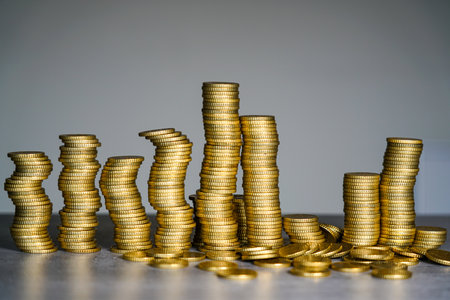 Concept image of unstable stacks of gold coins representing financial instability, market volatility, economic imbalance, and risk in global financeの写真素材