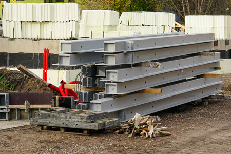 Stack of steel beams, insulation panels, and pipes on construction site prepared for modern building assembly and structural installationの写真素材