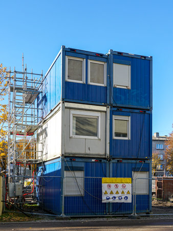 Three-story blue modular containers used as site offices or housing at a construction site. Safety...