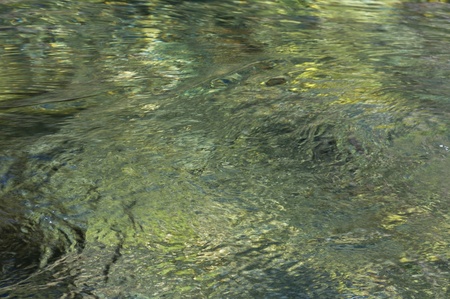 Rippled background showing pebbles through clear waterの写真素材