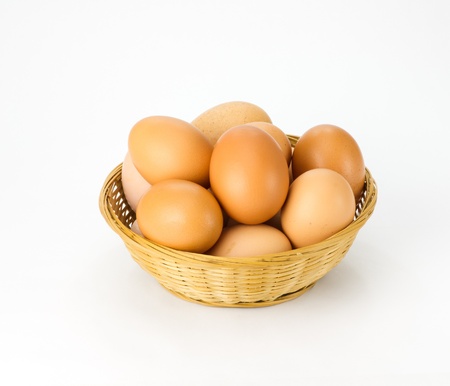 Fresh brown eggs in wicker basket on whiteの写真素材