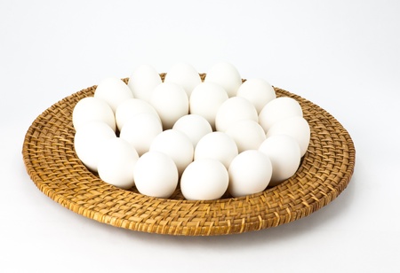 Fresh white eggs arranged on a wicker trayの写真素材