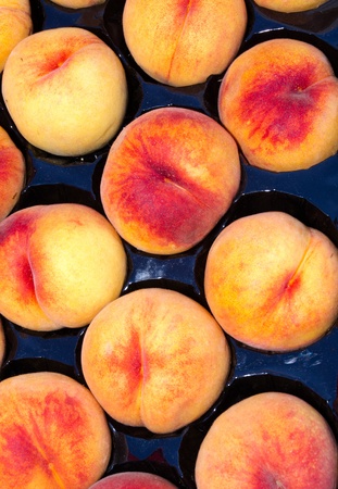 Fresh peaches on display in black tray at the farmerの写真素材