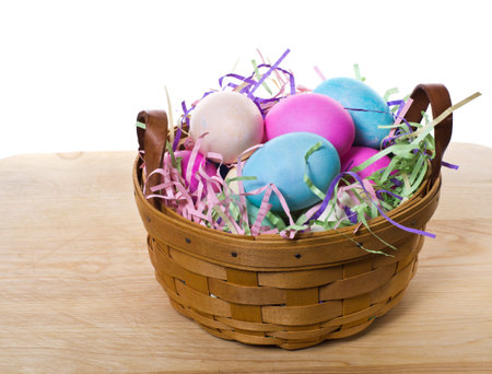A large wicker basket of colorful dyed Easter eggs sitting on a table