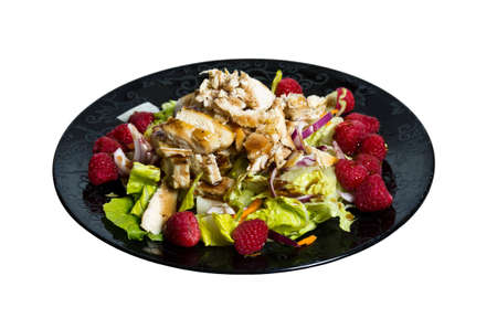 A raspberry chicken salad with dressing on a black plateの写真素材