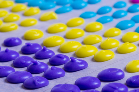 A tray of colorful homemade purple and yellow candy dotsの写真素材