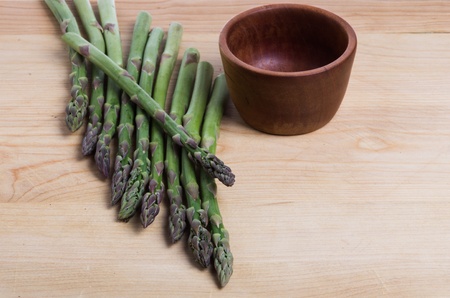Asparagus spears and wooden bowl on cutting boardの写真素材