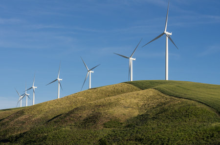 A row of wind turbines on a sunny hill
