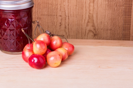 Cherry jam and fresh ripe cherries on wooden tableの写真素材