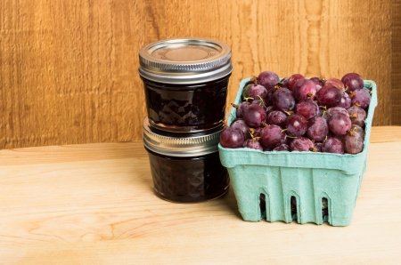 Gooseberry jam and red gooseberries on wooden tableの写真素材