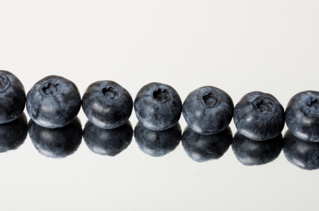 Row of fresh blueberries on shiny reflective surfaceの写真素材