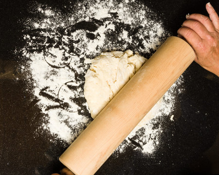 A baker rolling out dough for biscuits