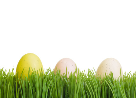 Three colorful Easter eggs on green grass isolated