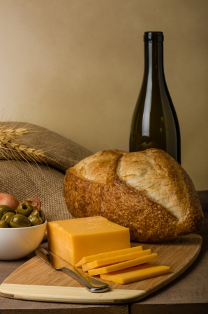 A still life with sausage cheese olives wine bottle and bread on a cutting boardの写真素材