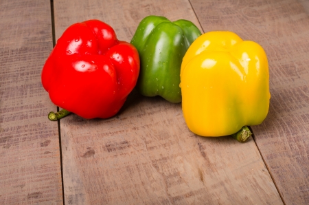 Three colorful bell peppers on a wooden tableの写真素材