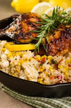 Cast iron skillet with lemon chicken and rice and roasted corn seasoned with rosemaryの写真素材