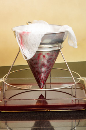Filtering fresh strawberries through cheese cloth to make jelly