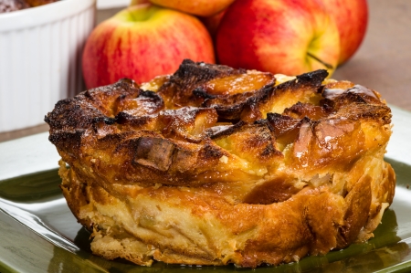 Apple bread pudding on green plate with apples and bowlの写真素材