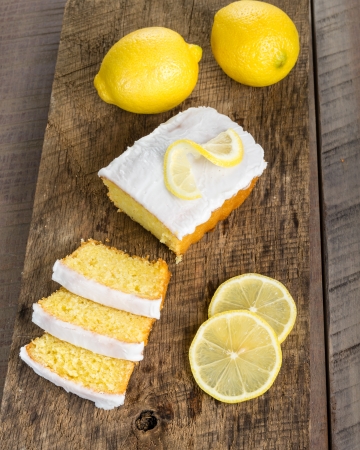 Sliced lemon pound cake with white icing and lemonsの写真素材