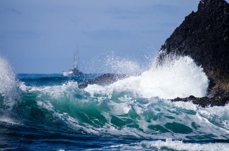 A small fishing boat navigating just outside rough surfの写真素材