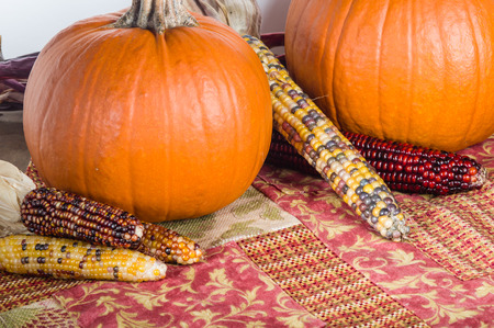 Orange pumpkin display with colorful ears of cornの写真素材