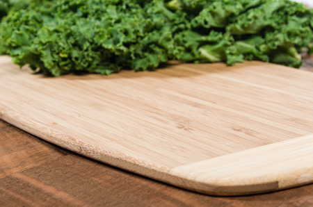 Curly green kale leaves on bamboo cutting boardの写真素材