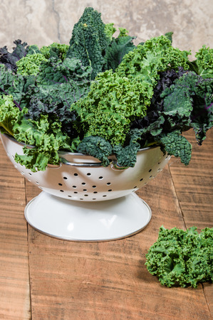 Red and green kale leaves in a white colanderの写真素材