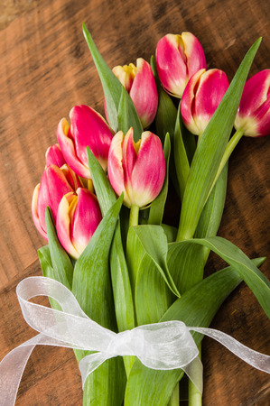 Bouquet of fresh pink and yellow tulips on a wooden tableの写真素材