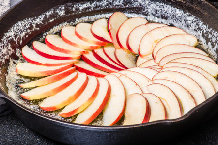 Apple slices arranged in skillet to make apple cakeの写真素材