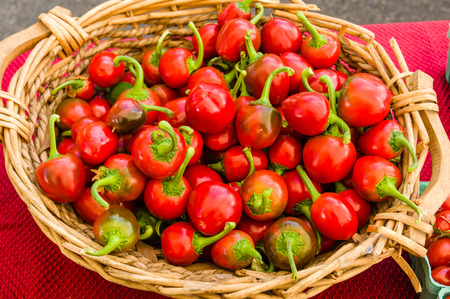 Red hot cherry peppers displayed in basket at the marketの写真素材