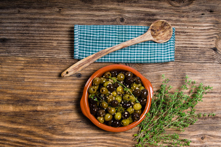 Bowl of green and black olives with wooden spoonの写真素材
