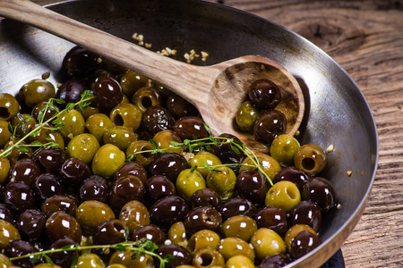 Olives and thyme in skillet with wooden spoonの写真素材