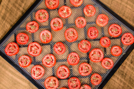 Slices of seasoned tomatoes on a drying rack for preserving