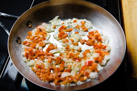 Red peppers and onions sauting in fry pan on the stoveの写真素材