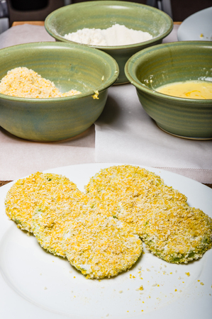 Applying cornmeal dredge to tomato slices to prepare for fryingの写真素材