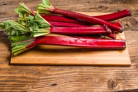 Fresh red rhubarb stalks on a wooden cutting boardの写真素材