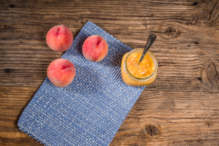 Ripe juicy yellow peaches and jam on a rustic wooden tableの写真素材
