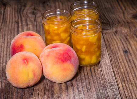 Ripe yellow peaches and jars of preserves or pie fillingの写真素材
