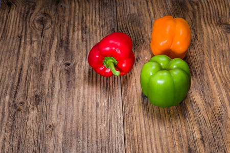 Fresh colorful bell peppers arranged on a rustic tableの写真素材